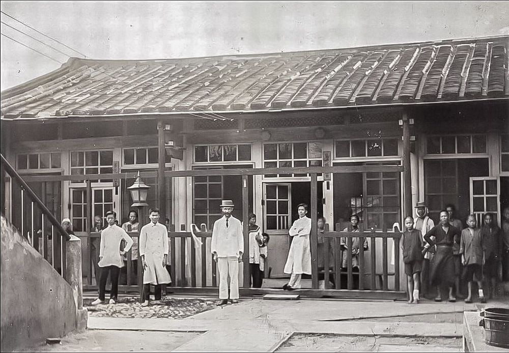 第一代彰基後棟（原作名稱：1910年代第一代醫院後棟一層樓建築及病人。典藏者：彰基文史博物館。發佈於《彰基文史博物館文史資料庫》[http://cchhmuseum.org/archive/detail.php?sid=926]）照片提供者：彰基文史博物館藏／拍攝年份：1910