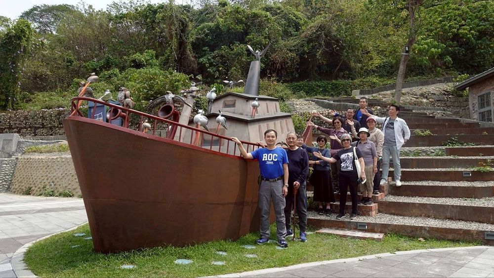 眷戶志工在名為「同舟」的公共藝術旁合影，緬懷父輩搭船撤退來台的歲月。(照片提供：林達祐)