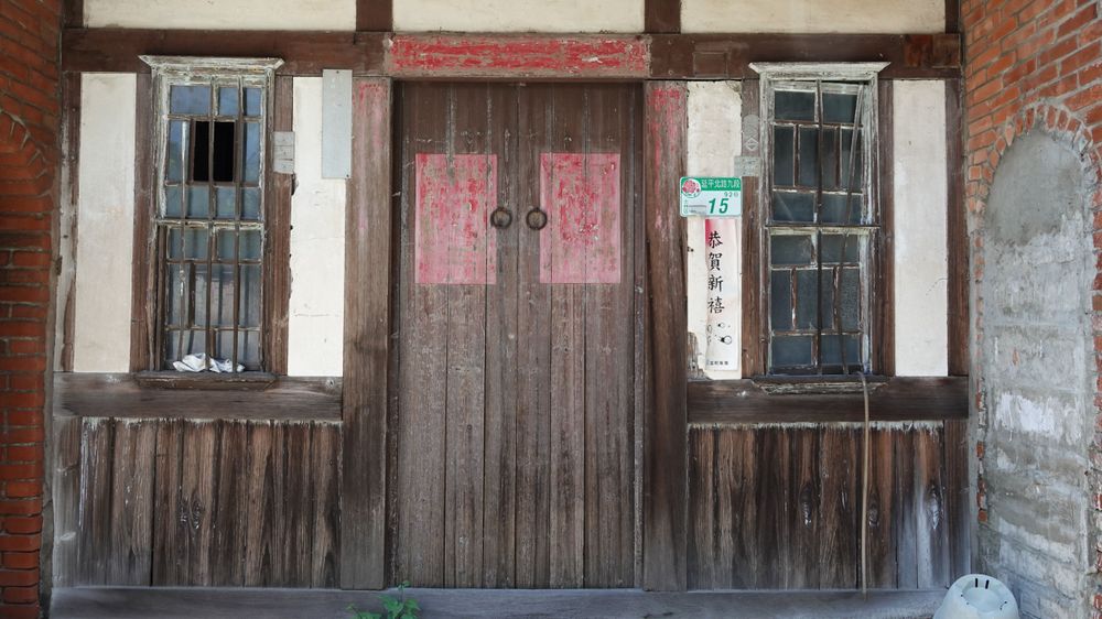 宅體正身立面為「凹壽」形式；外牆多為磚造，正門設木板雙開門，兩側開洋式上下推拉窗，窗扇分割細緻、保存良好，窗上並以突出磚線腳收邊，立面層次鮮明。／資料來源：毛毓翔拍攝（2025年4月23日）。