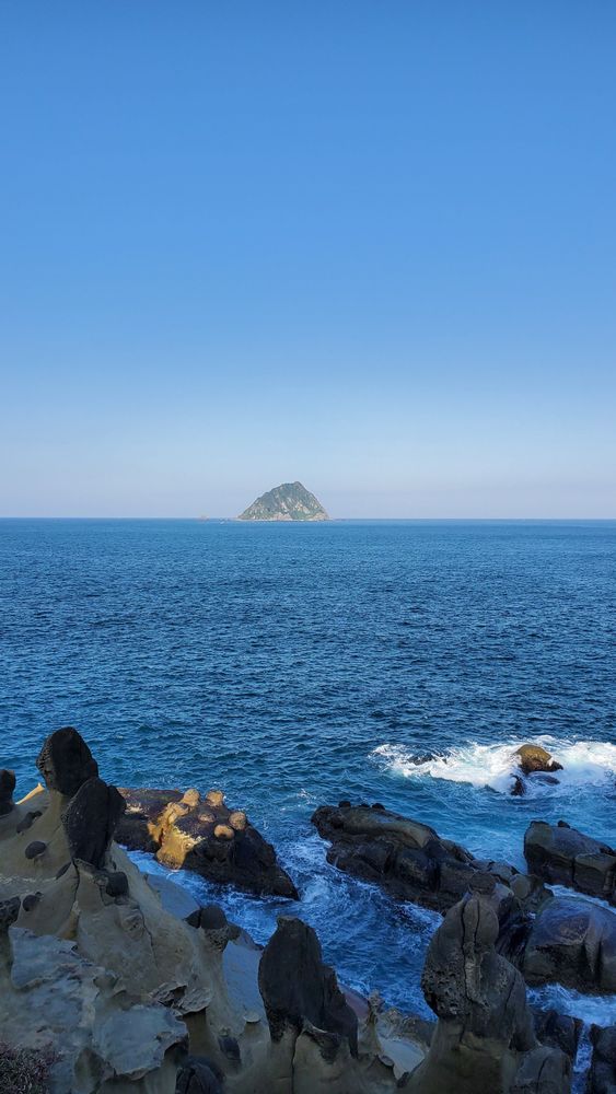 眺望青空與湛藍海面的交界，可見基隆嶼靜靜矗立著。拍攝者：王懷璿∕拍攝日期：2025/12/16