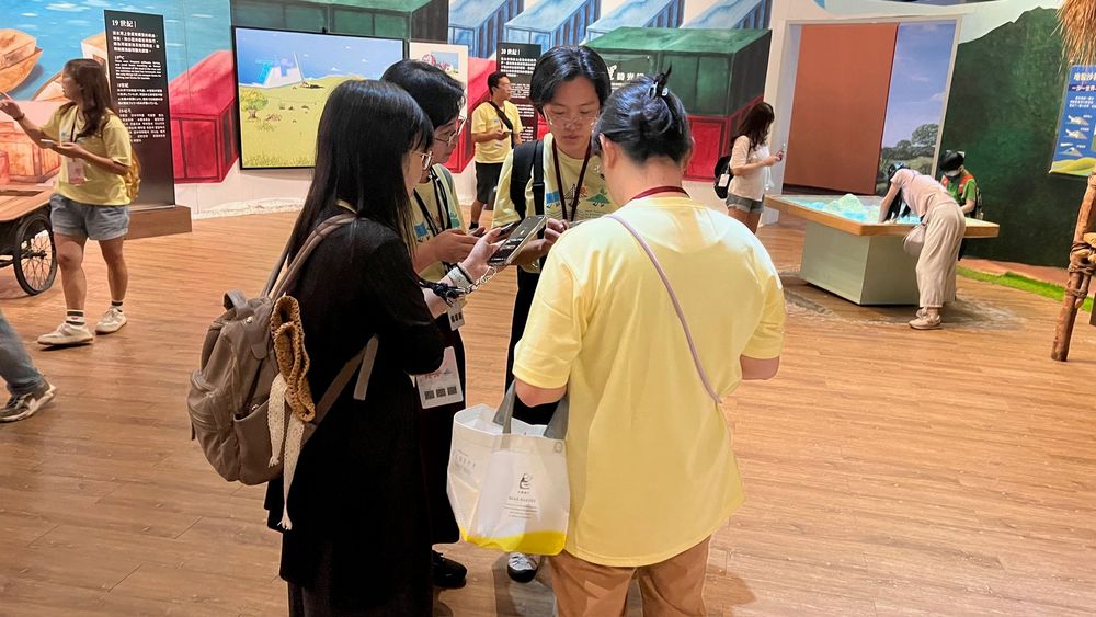 手機螢幕的微光映在臉上，學員分組討論、交叉比對答案。從 19 世紀航運到 20 世紀臺北港，時間軸上的每一格都是解謎關鍵。（照片提供者：林英斌 / 拍攝日期：2026.08.11）