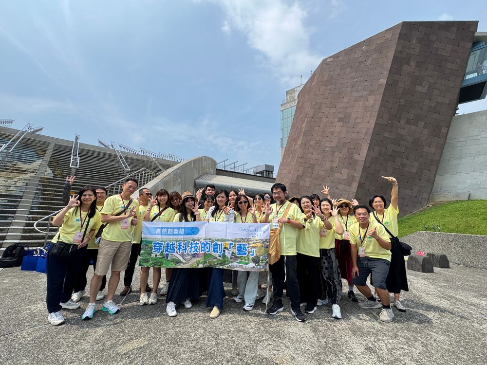 解謎完成，自然創藝組在十三行博物館前合影，舉起「穿越科技的創藝」旗幟，準備搭車前往下一站挖仔尾踏查。（照片提供者：新北市教育局 / 拍攝日期：2026.08.11）