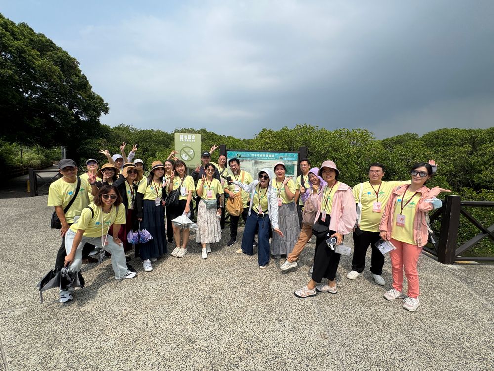 全員在挖子尾自然保留區解說牌前大合照，比出勝利手勢，笑容燦爛。走過紅樹林步道的濕地導覽，一場動人的生態學習在此留下歡樂的集體記憶。（照片提供者：新北市教育局 / 拍攝日期：2026.08.11）