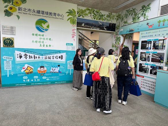 學員步入新北市永續環境教育中心，牆面寫著「保護地球，珍惜所有，永續環境，尊重生命」，一旁「淨零新動力」節能展區，引導大家思考日常減碳的行動。（照片提供者：許大偉 / 拍攝日期：2026.08.11）